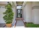 Inviting front entrance with a black door, decorative shrub, and tiled walkway at 3718 Beneraid St, Land O Lakes, FL 34638