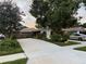 Charming home featuring lush landscaping, mature trees, and a spacious driveway under a beautiful sunset at 402 Evergreen Dr, Oldsmar, FL 34677