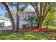 A two-story home with a charming balcony stands proudly framed by mature trees and lush landscaping at 408 Georgia Ave, Crystal Beach, FL 34681