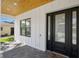Covered front porch with a modern black front door, brick pavers, and wood ceiling at 4114 W Neptune St, Tampa, FL 33629