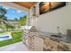 Outdoor kitchen featuring stone accents, granite countertop, sink, and grill at 4114 W Neptune St, Tampa, FL 33629
