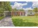 Charming single-story home with red brick accents, a spacious lawn, and mature landscaping at 505 Broxburn Ave, Temple Terrace, FL 33617