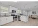 Bright kitchen featuring stainless steel appliances, granite counters, white cabinetry, and wood-look floors at 505 Broxburn Ave, Temple Terrace, FL 33617