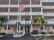 Exterior shot of a multi-story residential building with balconies and a flagpole displaying the American flag at 6025 Shore S Blvd # 408, Gulfport, FL 33707
