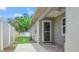 Exterior of the home with a small patio, white fence, lush greenery, and lawn mower at 7021 Blossom Ave, Tampa, FL 33614