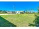 Large backyard featuring green grass, a new home, and some trees and bushes at 7061 Denmark St, Englewood, FL 34224