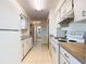 Galley kitchen features white appliances and tile flooring at 7061 Denmark St, Englewood, FL 34224