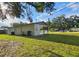 Exterior view of home with lush green backyard, covered patio, and mature shade tree at 8017 Tudor Pl, Tampa, FL 33610