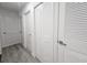 Hallway with gray wood floors and white doors, including a closet with shuttered door at 8017 Tudor Pl, Tampa, FL 33610