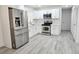 Updated kitchen featuring stainless steel appliances, white cabinetry, and gray wood-look flooring at 8017 Tudor Pl, Tampa, FL 33610