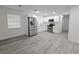 Bright kitchen with white cabinetry, stainless steel appliances, and gray wood-look flooring at 8017 Tudor Pl, Tampa, FL 33610