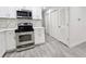 Updated kitchen featuring stainless steel appliances, white cabinetry, and gray wood-look flooring at 8017 Tudor Pl, Tampa, FL 33610