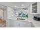 Open-concept kitchen with white cabinets, a stainless steel sink, and a view into the living room and water beyond at 8211 Brent St # 815, Port Richey, FL 34668