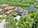 Aerial view of a large luxury home with mature landscaping, a driveway and a view of the waterway at 8707 Silverthorn Rd, Seminole, FL 33777