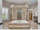 A large soaking tub is encased in marble with direct access to the custom walk-in closet at 8707 Silverthorn Rd, Seminole, FL 33777