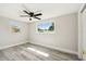 Light filled bedroom with windows, wood-look floors, and modern ceiling fan at 10831 Manchester Rd, Port Richey, FL 34668