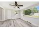 Bright bedroom with large windows, wood-look flooring, modern ceiling fan and neutral paint at 10831 Manchester Rd, Port Richey, FL 34668