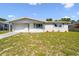 Charming single-story home featuring a well-maintained lawn, garden bed, and attached garage under a blue sky at 10831 Manchester Rd, Port Richey, FL 34668