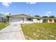 Charming single-story home featuring a well-maintained lawn, garden bed, and attached garage under a blue sky at 10831 Manchester Rd, Port Richey, FL 34668