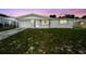 Charming single-story home featuring a well-maintained lawn and attached garage with a beautiful sunset sky at 10831 Manchester Rd, Port Richey, FL 34668