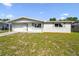 Charming single-story home featuring a well-maintained lawn and attached garage under a blue sky at 10831 Manchester Rd, Port Richey, FL 34668