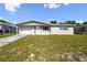 Charming single-story home featuring a well-maintained lawn and attached garage under a blue sky at 10831 Manchester Rd, Port Richey, FL 34668