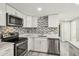 Updated kitchen boasts white cabinets, stainless steel appliances, and modern backsplash at 10831 Manchester Rd, Port Richey, FL 34668