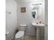 A half bath featuring a toilet, pedestal sink, an oval mirror, and neutral tile flooring at 10921 Cory Lake Dr, Tampa, FL 33647