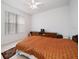 Cozy bedroom featuring neutral walls, a patterned orange bedspread, and a window with blinds at 10921 Cory Lake Dr, Tampa, FL 33647