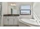 Bright bathroom featuring a soaking tub, a large mirror, and a sleek vanity with dark countertop at 11311 Striped Bass Ct, New Port Richey, FL 34654