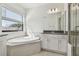 Sunlit bathroom showcases a modern soaking tub, glass-enclosed shower, and vanity with dark countertop at 11311 Striped Bass Ct, New Port Richey, FL 34654