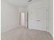 Neutral carpeted bedroom with closet, bright white walls and open doorway to another room at 11311 Striped Bass Ct, New Port Richey, FL 34654