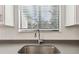 Close up shot of a modern kitchen sink, dark countertops, and window with blinds at 11311 Striped Bass Ct, New Port Richey, FL 34654