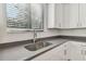 A close up of a kitchen sink and dark countertop beneath a window with blinds at 11311 Striped Bass Ct, New Port Richey, FL 34654