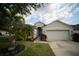 Charming single-story home with a two-car garage, manicured lawn, and tropical landscaping at 12721 Avelar Creek Dr, Riverview, FL 33578