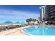 Resort-style pool area with ocean views, palm trees, lounge chairs, and turquoise umbrellas at 1540 Gulf Blvd # 2107, Clearwater Beach, FL 33767
