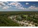 Community aerial shot featuring mature trees, a golf course, and a lake under a partly cloudy sky at 16304 Wild Mallard Dr, Odessa, FL 33556