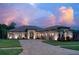 Charming single-story home at dusk, featuring a paver driveway, lush landscaping, and a three-car garage at 16304 Wild Mallard Dr, Odessa, FL 33556