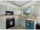 Functional kitchen area with black appliances, vintage aqua cabinetry, and a bright window view at 1741 Elk Spring Dr, Brandon, FL 33511