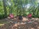 Secluded backyard sitting area with two chairs and a fire pit surrounded by mature trees and lush greenery at 2328 Harn Blvd, Clearwater, FL 33764