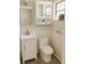 A bathroom features a vanity, toilet, a mirror cabinet, and a window, offering essential amenities and storage at 2328 Harn Blvd, Clearwater, FL 33764