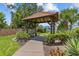 Charming tile roof gazebo with wooden beam construction and bench, surrounded by lush green landscaping at 2420 Winding Creek Blvd # 209, Clearwater, FL 33761