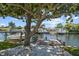 A waterfront dock featuring a boat lift, adjacent to a patio with seating and a scenic water view at 336 Westwinds Cir, Palm Harbor, FL 34683