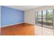A cozy bedroom with beautiful hardwood flooring, a bright blue accent wall, and sliding doors to the balcony at 3368 Ramblewood Pl # 37-D-1, Sarasota, FL 34237
