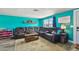 Spacious living room with a leather sectional sofa, bright teal walls, and lots of natural light at 3427 Cantrell St, Holiday, FL 34690