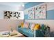 Cozy living room with a blue sofa, colorful artwork, and playful decorations on the half-painted walls at 36972 Sagemoor Dr, Zephyrhills, FL 33541