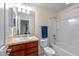Well-lit bathroom with a shower-tub combination, wood vanity, large mirror, and a neutral color palette at 5239 Fallen Leaf Dr, Riverview, FL 33578