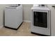 Modern laundry area showcasing a white washer and dryer set, complemented by neutral-toned tile flooring at 5239 Fallen Leaf Dr, Riverview, FL 33578