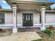 Close-up of the home's entryway featuring a stylish dark door with decorative columns and manicured landscaping at 5580 S Salford Blvd, North Port, FL 34287