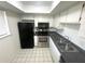 Compact kitchen features stainless steel appliances, black countertops, and white cabinets at 6342 Newtown Cir # A4, Tampa, FL 33615